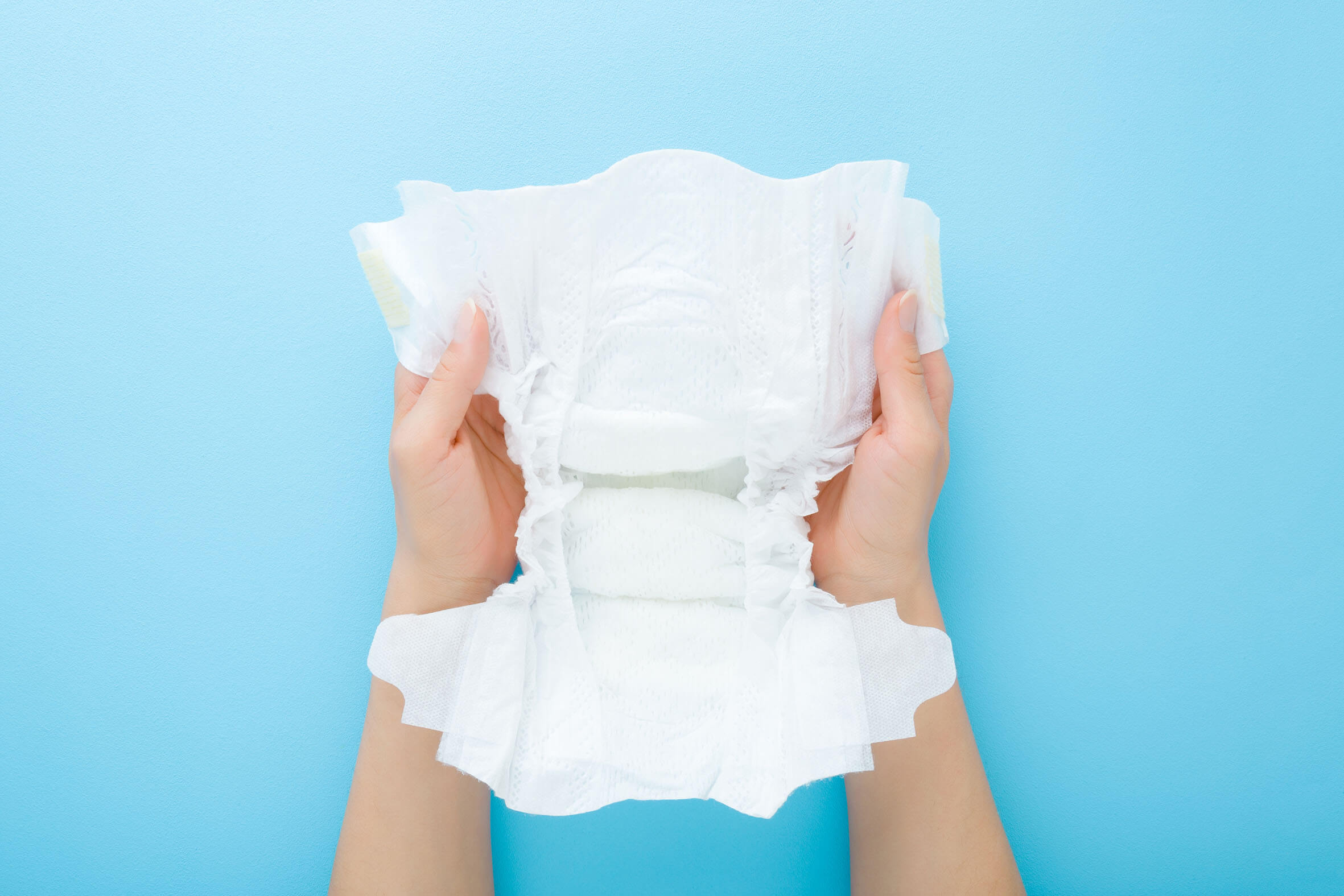 Twee handen met die een absorberende kinderluier vasthouden